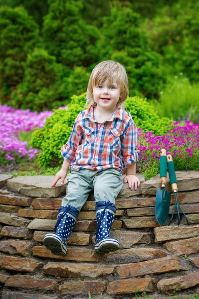 Mladého zahradníka pózuje na květinového záhonu — Stock fotografie
