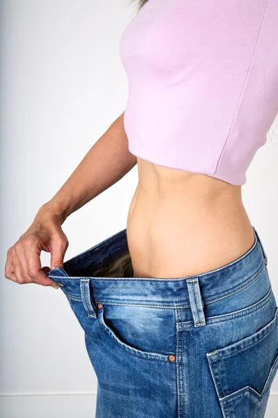 Slim female showing big jeans — Stock Photo, Image