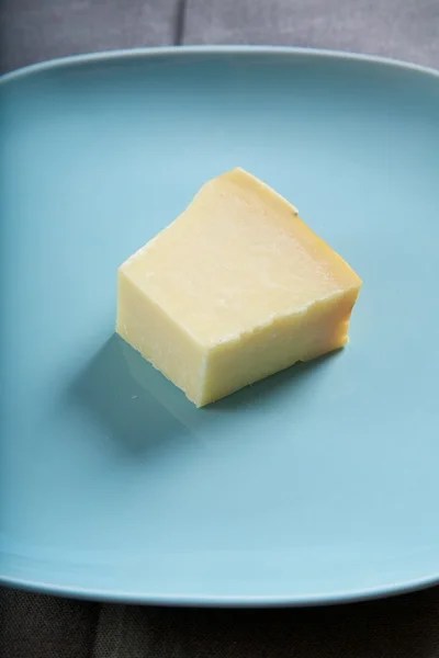 Pedazo de queso en el plato azul — Foto de Stock
