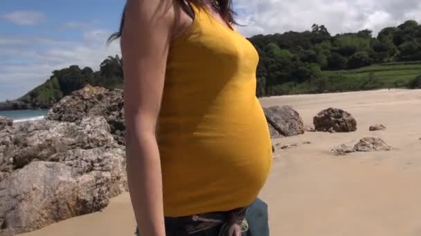 Желтый живот беременной, гуляющей на пляже — стоковое видео