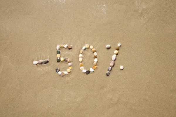 Cincuenta por ciento de descuento piedras en la playa de arena — Foto de Stock