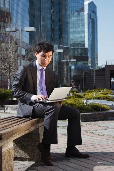 Young businessman sitting with laptop. Outdoor. — Stock Photo, Image