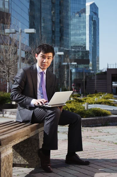 Молодий бізнесмен сидить з ноутбуком. На відкритому повітрі . — стокове фото