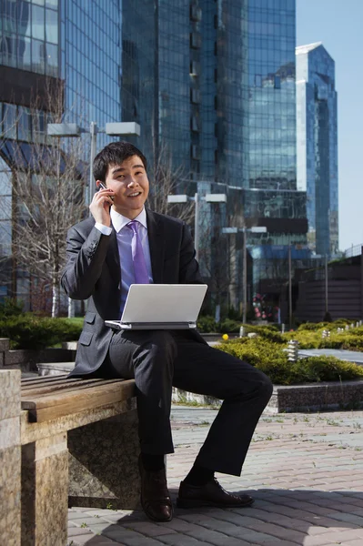 Молодой бизнесмен сидит с ноутбуком. На открытом воздухе . — стоковое фото