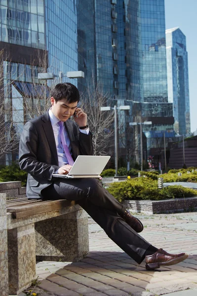 Tânărul om de afaceri stă cu laptopul. În aer liber . — Fotografie, imagine de stoc
