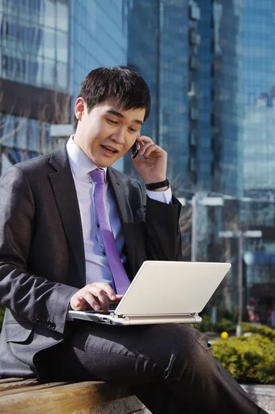 Jeune homme d'affaires assis avec un ordinateur portable. Extérieur . — Photo