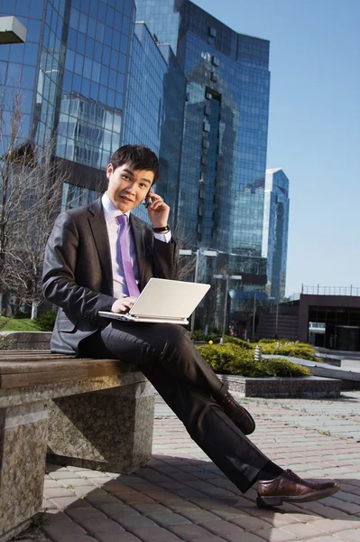 Молодий бізнесмен сидить з ноутбуком. На відкритому повітрі . — стокове фото