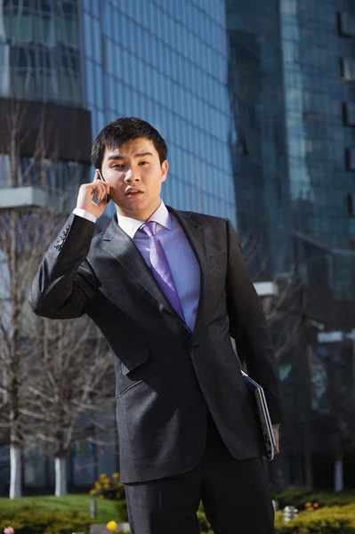 Young businessman standing and talking on mobile phone — Stock Photo, Image