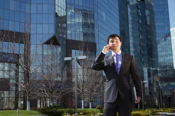 Young businessman standing and talking on mobile phone — Stock Photo, Image