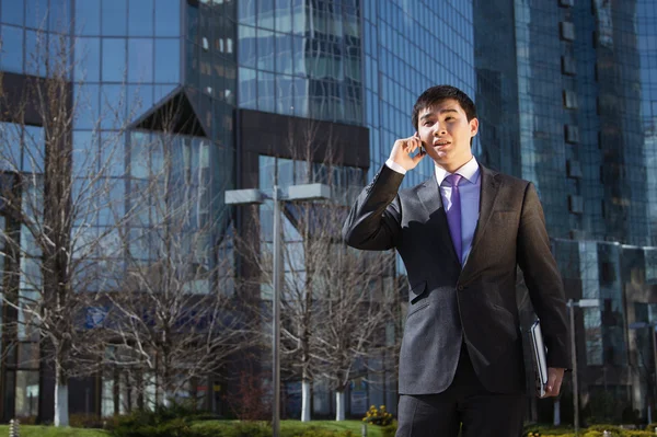 Joven hombre de negocios de pie y hablando por teléfono móvil — Foto de Stock