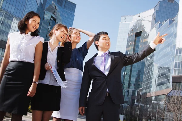 Happy diverse group of executives pointing over business center. — Stock Photo, Image