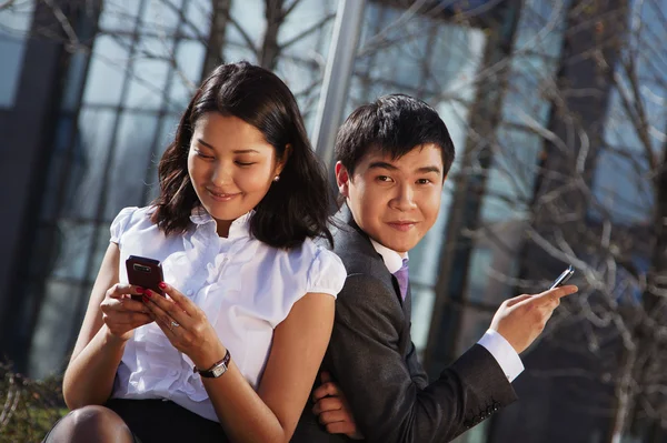 Zakelijke paar zittend op de Bank chatten met mobiele telefoon — Stockfoto