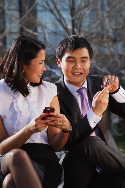 Деловая пара сидит на скамейке и разговаривает с мобильным телефоном — стоковое фото