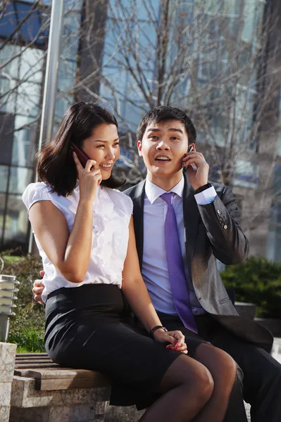 Casal de negócios sentado no banco conversando com telefone celular — Fotografia de Stock