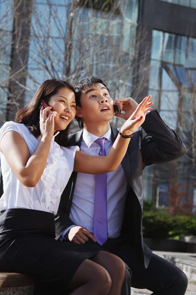 Casal de negócios sentado no banco conversando com telefone celular — Fotografia de Stock