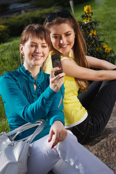 Krásná dívka s přítelkyní a povídání s mobil — Stock fotografie