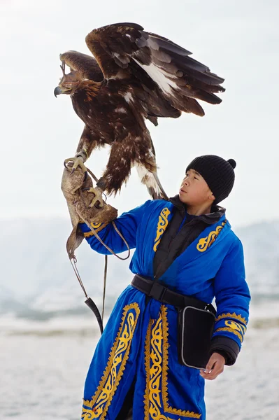 NURA, KAZAKHSTAN - FEBRUARY 23: Eagle on kid's hand in Nura near Almaty on February 23, 2013 in Nura, Kazakhstan. The traditional event happens yearly and the place becomes as a medieval times city. — Stock Photo, Image