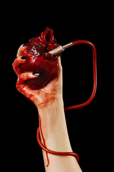 Coração humano na mão com tubo, cabo vermelho isolado em preto — Fotografia de Stock