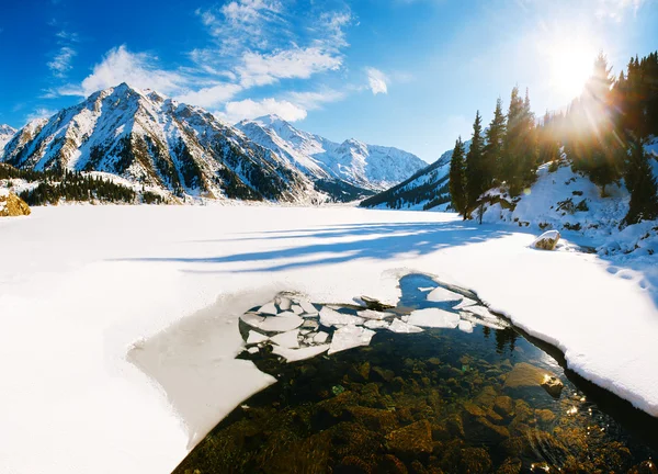 Big Almaty lake on december. Water, ice, mountains and snow.