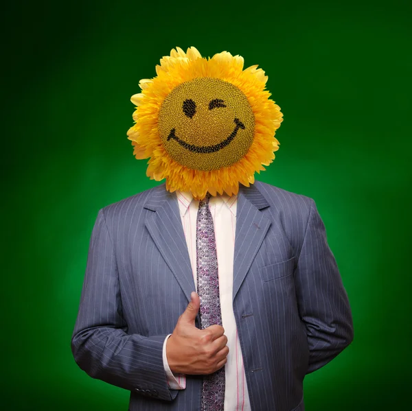 Smiling sunflower head man in suit coat with present thumbs up o — Stock Photo, Image