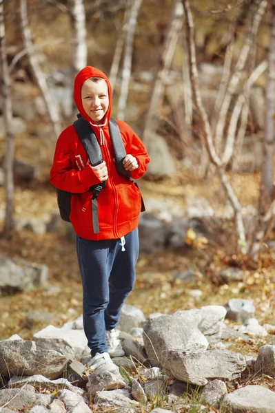 Usmívající se turista šťastlivce s batohem v lese. oblečený v červené barvě — Stock fotografie