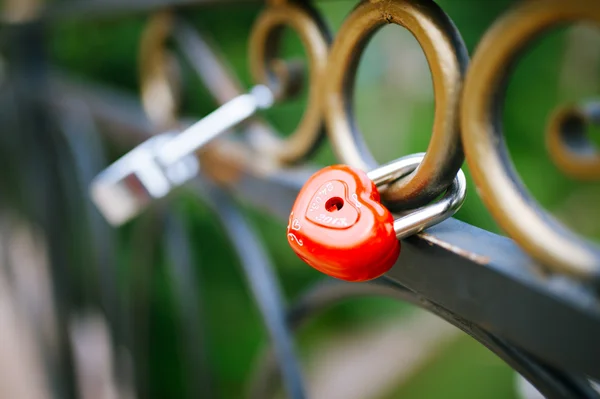 Rött lock i hjärta form på bron, suddiga bakgrunden — Stockfoto