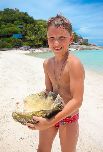 Μεγάλο κοχύλι που κατέχονται από ένα νεαρό αγόρι στην παραλία — Φωτογραφία Αρχείου
