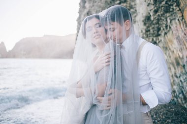 Güzel çift deniz üzerinde kapalı bir peçe, gülen, gülümseyen, mutlu, düğün günü, aşk hikayesi