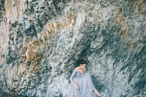 美丽的新娘 身穿蓝色长裙 坐在悬崖边 朝下看去 — 图库照片