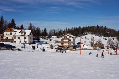 SZCZYRK, POLAND, FEBRUARY 2022: Silesian Beskid Dağları 'ndaki beyaz yamaçta kayakçılar Avrupa Bialy Krzyz' de, açık mavi gökyüzü soğuk kış gününde.