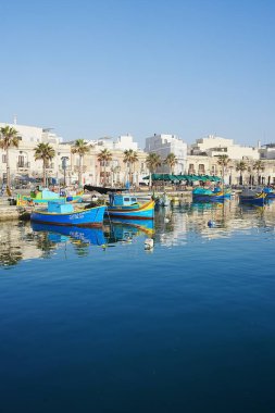 Scenic promenade with boats in Marsaxlokk town in Malta - vertical