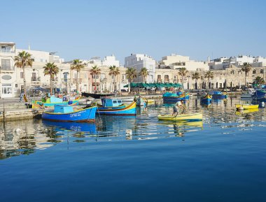 Promenade with beautiful boats in european Marsaxlokk village in Malta in 2022 warm sunny spring day on May.