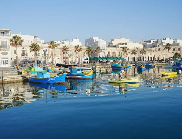 Promenade with beautiful boats in european Marsaxlokk village in Malta in 2022 warm sunny spring day on May.
