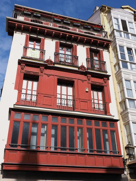 Facade of red house in european Bilbao city at Biscay province in Spain, clear blue sky in 2019 warm sunny summer day on September - vertical