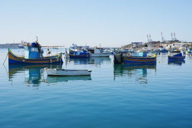 Malta 'nın Marsaxlokk köyünde geleneksel tekneler, Mayıs' ın 2022 'de güneşli bahar gününde açık mavi gökyüzü.