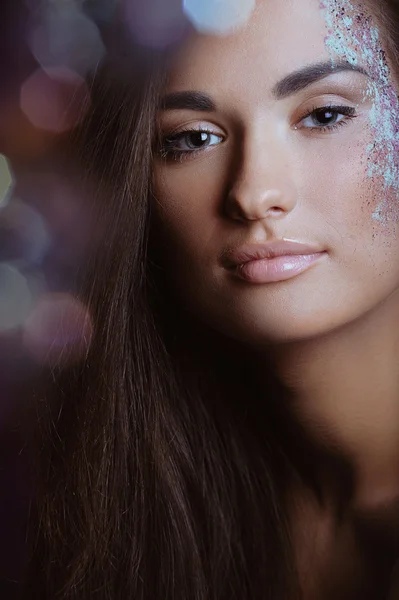 Beautiful woman with festive makeup in color spray and boke lights — Stock Photo, Image