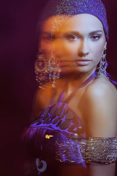 Glamour fille en robe de soirée violette et de beaux bijoux en mouvement lumières flou — Photo