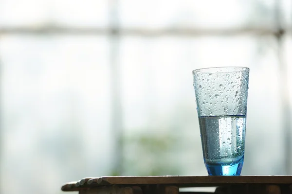 vaso de agua mineral en la mesa frente a ventana