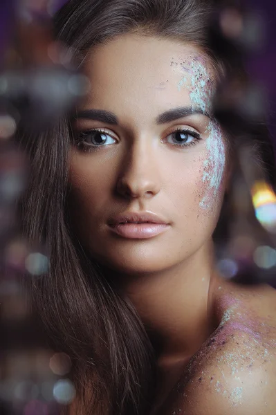 Beautiful woman with festive makeup in color spray and boke lights — Stock Photo, Image