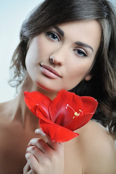 Schöne Frau mit frischer, gesunder Gesichtshaut und roter Blume in der Hand — Stockfoto