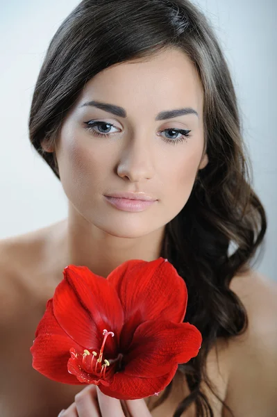 Mulher bonita com pele de saúde fresca de cara e flor vermelha na mão — Fotografia de Stock