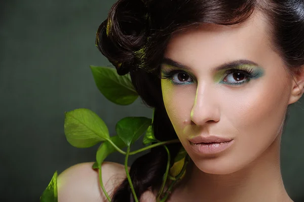 Όμορφη γυναίκα με πράσινο συνθέτουν και μερικά φύλλα στα μαλλιά της — Φωτογραφία Αρχείου