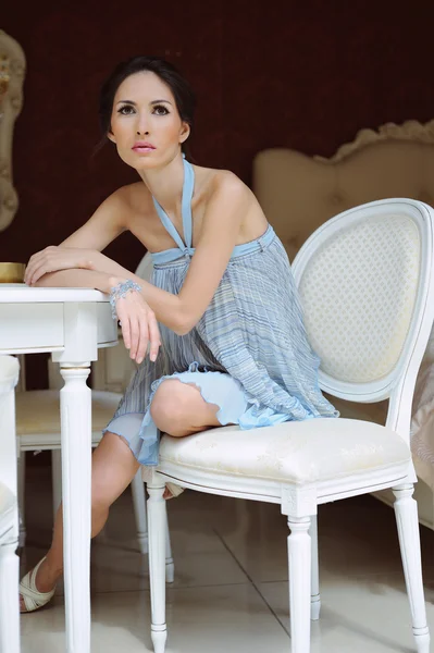 Schöne junge Frau sitzt in einem Stuhl in raffiniertem Interieur — Stockfoto