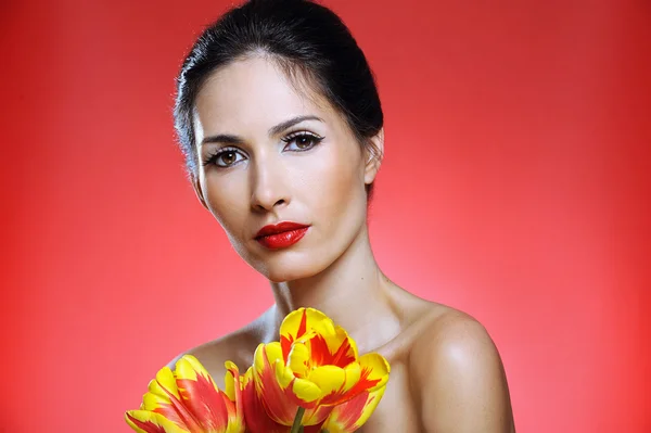 Belle femme avec un maquillage lumineux tenant des tulipes — Photo