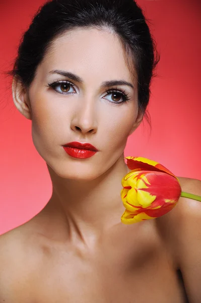 Schöne Frau mit hellem Make-up hält Tulpen — Stockfoto