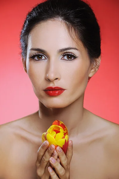 Hermosa mujer con tulipán en sus manos sobre fondo rojo — Foto de Stock