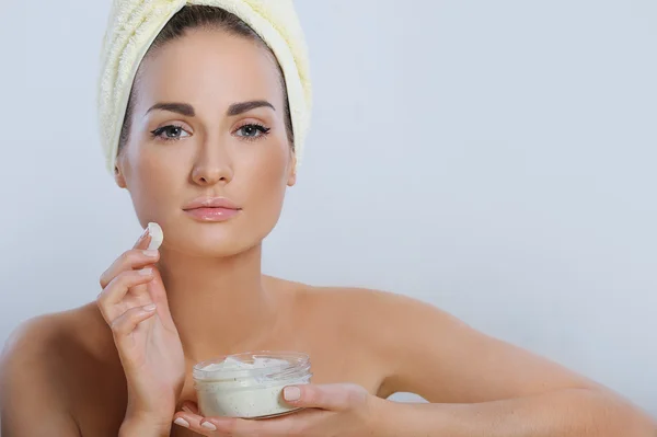 Young beautiful woman touching her face and applying moisturizer to her skin — Stock Photo, Image