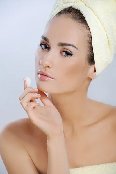 Junge schöne Frau berührt ihr Gesicht und trägt Feuchtigkeitscreme auf ihre Haut auf — Stockfoto