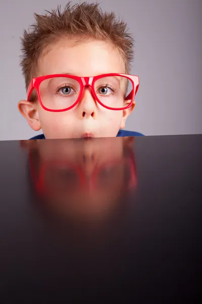 Fünf Jahre alte kleine süße Junge versteckt sich hinter einem Tisch — Stockfoto