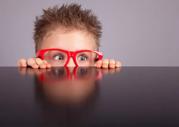 Fem år gammal liten söt pojke gömmer sig bakom ett bord — Stockfoto